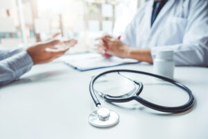 Doctors And Patients Consulting And Diagnostic Examining Sit And Talk. At The Table Near The Window In The Hospital Medicine Concept