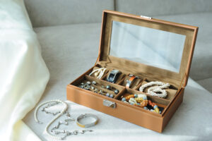 Leather Jewelry Box With Jewelry And Accessories Laid On A Couch