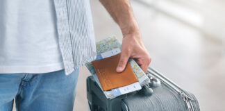 Man Holding His Passport And Carrying Suitcase, Close Up