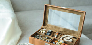 Leather Jewelry Box With Jewelry And Accessories Laid On A Couch