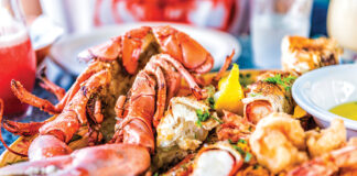 Macro Closeup Of Red Lobsters, Shrimp, Crab, Oyster And Seafood Platter On Plate In Restaurant With Tartar Sauce