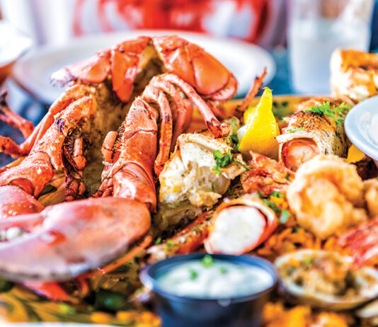 Macro Closeup Of Red Lobsters, Shrimp, Crab, Oyster And Seafood Platter On Plate In Restaurant With Tartar Sauce