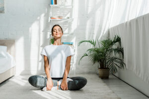 Beautiful Happy Girl With Closed Eyes Practicing Yoga In Lotus Position In Bedroom In The Morning