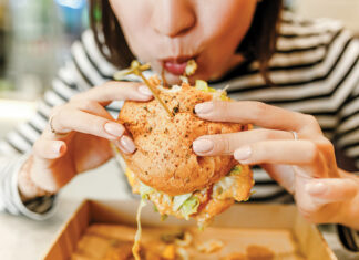 Woman Eating A Hamburger In Modern Fastfood Cafe, Lunch Concept