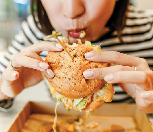 Woman Eating A Hamburger In Modern Fastfood Cafe, Lunch Concept