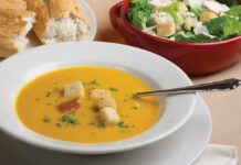 Pumpkin Soup With Garnish, Bread And Salad In The Background