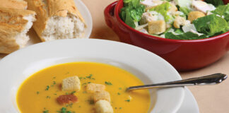 Pumpkin Soup With Garnish, Bread And Salad In The Background