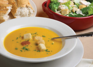 Pumpkin Soup With Garnish, Bread And Salad In The Background