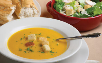 Pumpkin Soup With Garnish, Bread And Salad In The Background