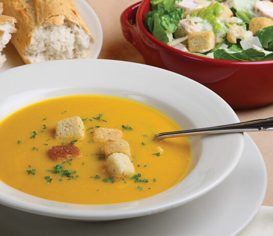 Pumpkin Soup With Garnish, Bread And Salad In The Background