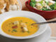 Pumpkin Soup With Garnish, Bread And Salad In The Background