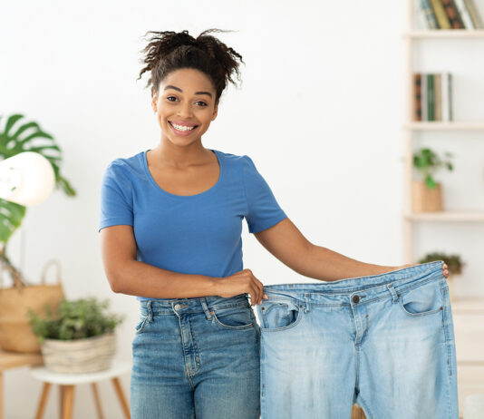 Happy Slim Black Girl Showing Old Jeans Standing At Home