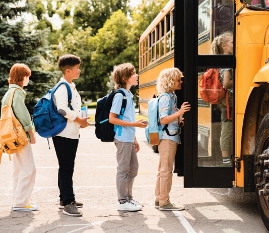 Multiethnic Mixed Race Pupils Classmates Schoolchildren Students Standing In Line Waiting For Boarding School Bus Before Starting New Educational Semester Year After Summer Holidays