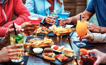 Group Of Friends Enjoying Appetizer Drinking And Eating In A Bar Close Up Of Hands Of Young People Holding Colorful Cocktails In The Happy Hour Time Social Gathering Party Time Concept