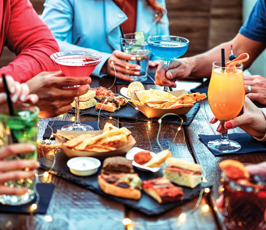 Group Of Friends Enjoying Appetizer Drinking And Eating In A Bar Close Up Of Hands Of Young People Holding Colorful Cocktails In The Happy Hour Time Social Gathering Party Time Concept