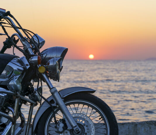 Motorcycle On The Sea Pier During A Beautiful Sea Sunset. Travel, Adventure, Vacation Concept