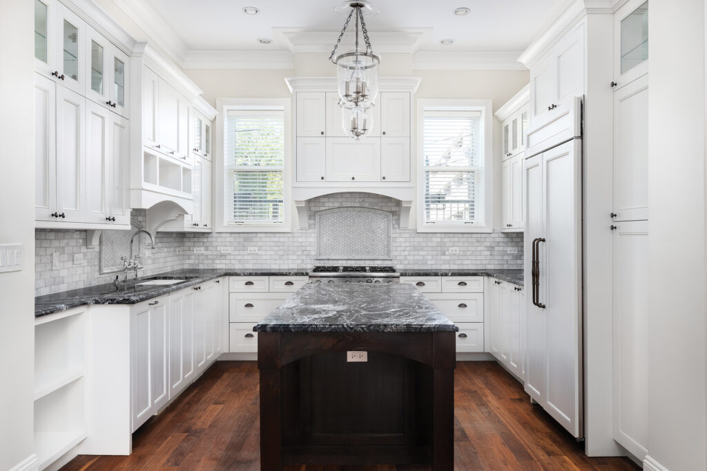 A Beautiful Kitchen With White Cabinets And Black Countertops.