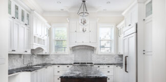 A Beautiful Kitchen With White Cabinets And Black Countertops.