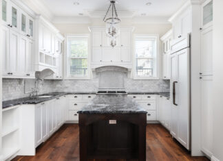 A Beautiful Kitchen With White Cabinets And Black Countertops.