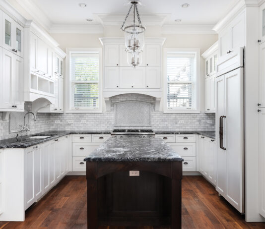 A Beautiful Kitchen With White Cabinets And Black Countertops.