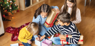 Cheerful Kids Discovering Christmas Presents At Home.